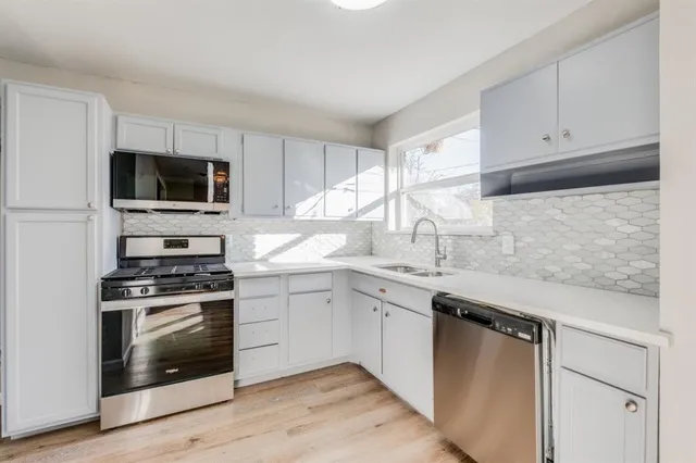 a kitchen with white cabinets and appliances