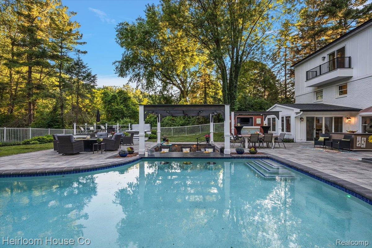 49001 Hanford Road Canton, MI 48187 - Photo 7 of 98 Expansive backyard featuring a large swimming pool with integrated steps, a paver patio surround, and a white picket fence