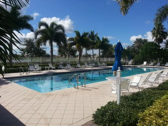a view of swimming pool with a patio and palm trees