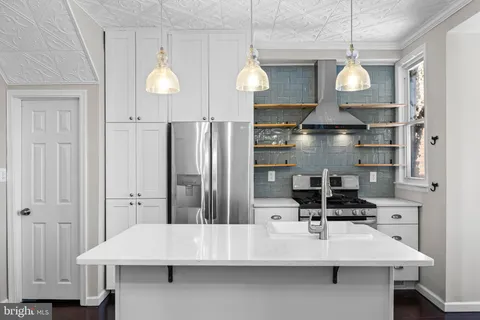 a kitchen with stainless steel appliances a refrigerator a sink dishwasher a stove and white cabinets with wooden floor