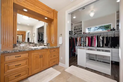 a bathroom with a granite countertop sink toilet a large mirror a shower and a bathtub