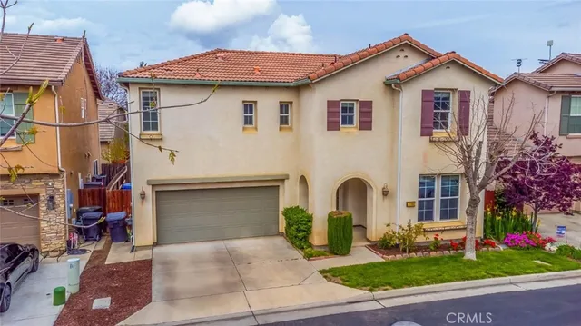 a view of a white house with a large windows and a yard with plants