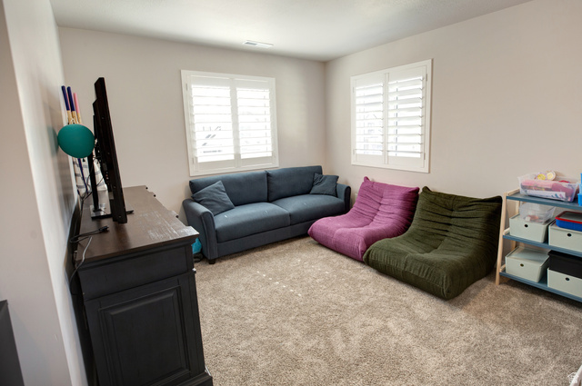 983 South 950 West Provo, UT 84601 - Photo 40 of 56 Carpeted room featuring two windows with white plantation shutters, a dark wood-finish media console, and light neutral wall tones
