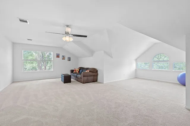 an empty room with windows and ceiling fan