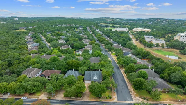 an aerial view of residential houses with outdoor space and trees