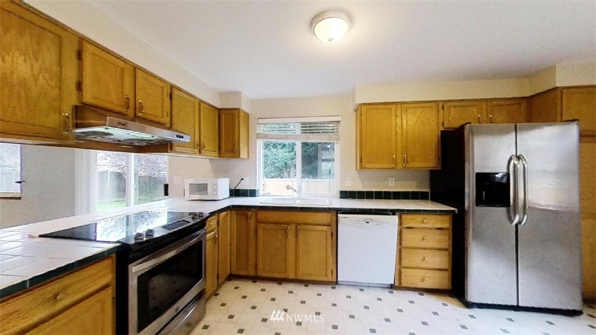 18607 104th Place Southeast Renton, WA 98055 - Photo 6 of 22 a kitchen with granite countertop a sink appliances cabinets and a counter top space