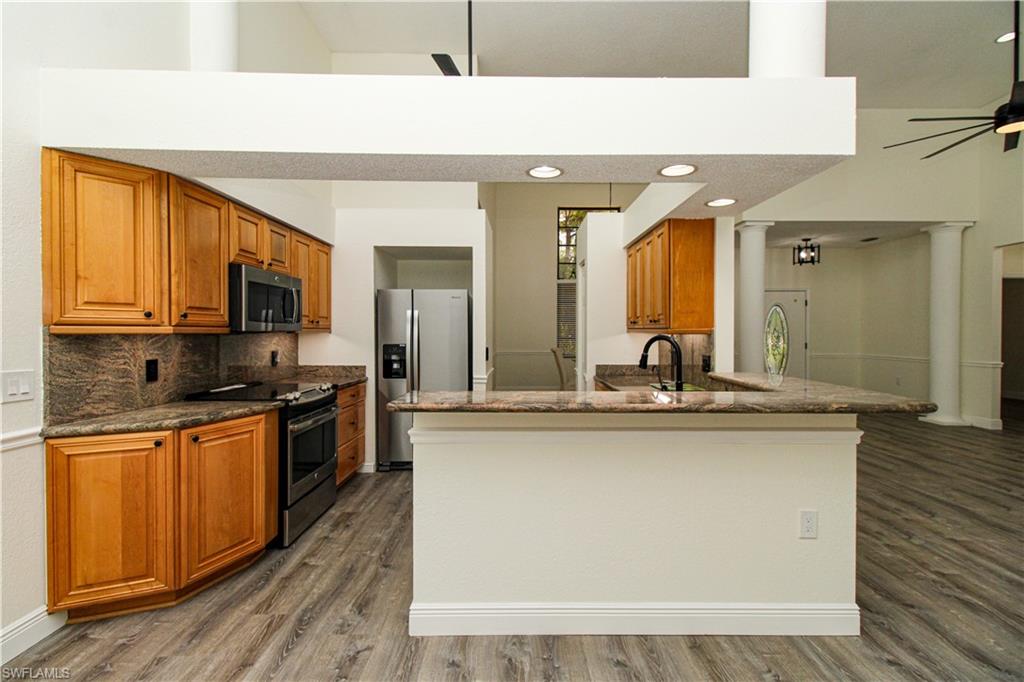 311 31st Street Northwest Naples, FL 34120 - Photo 23 of 50 a kitchen with stainless steel appliances granite countertop a sink a stove top oven and wooden floors