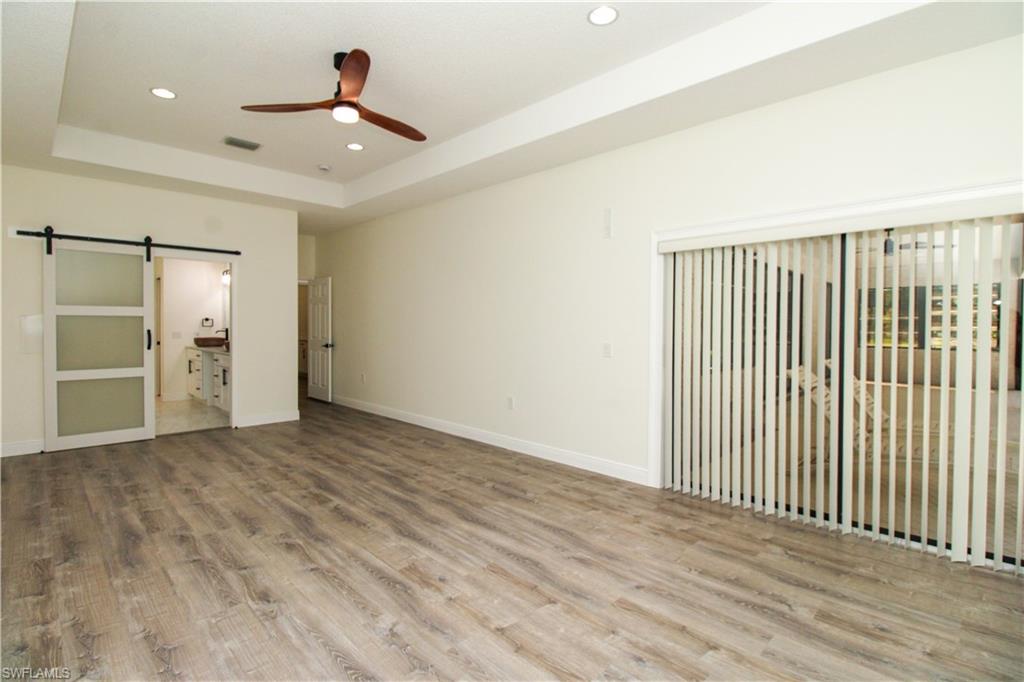 311 31st Street Northwest Naples, FL 34120 - Photo 44 of 50 an empty room with wooden floor chandelier fan and windows