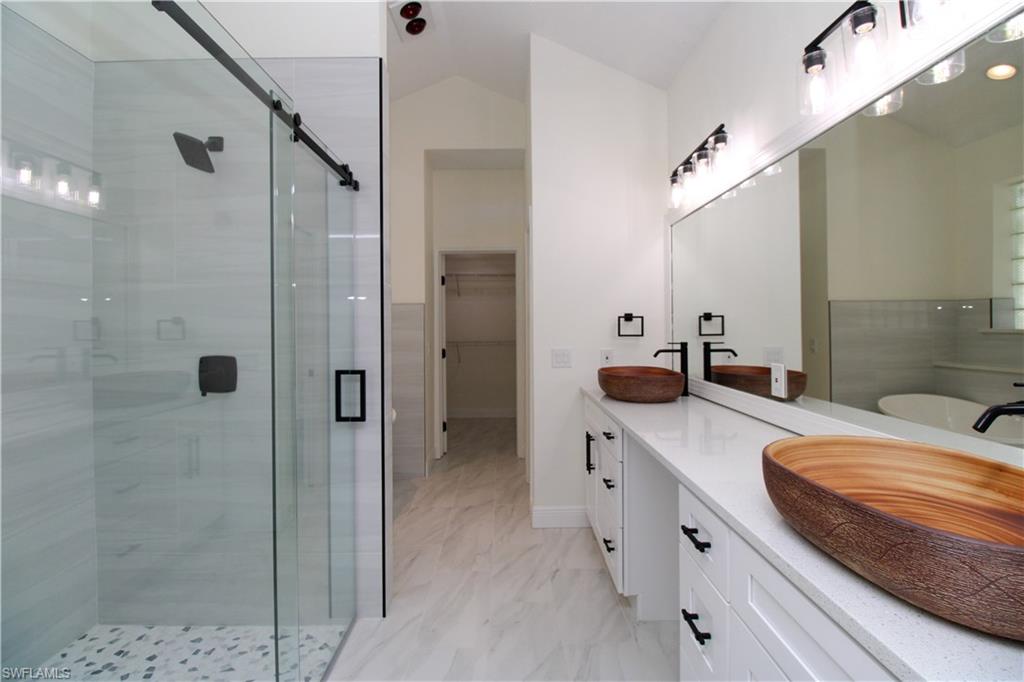 311 31st Street Northwest Naples, FL 34120 - Photo 45 of 50 a spacious bathroom with a double vanity sink a large mirror and shower