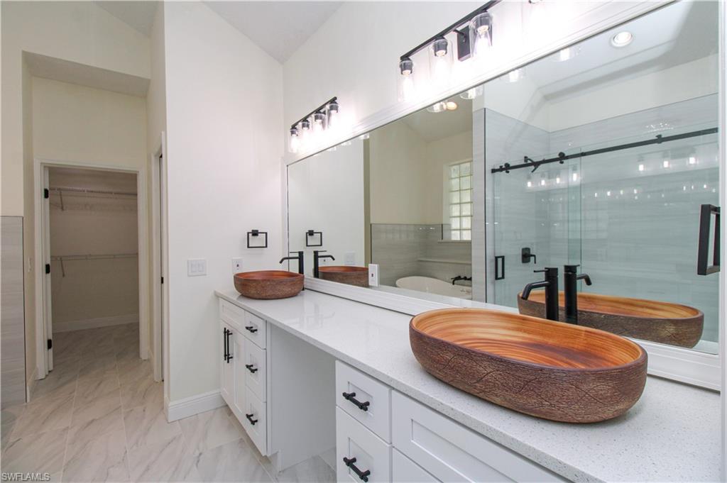 311 31st Street Northwest Naples, FL 34120 - Photo 46 of 50 a spacious bathroom with a double vanity sink a mirror and a bathtub