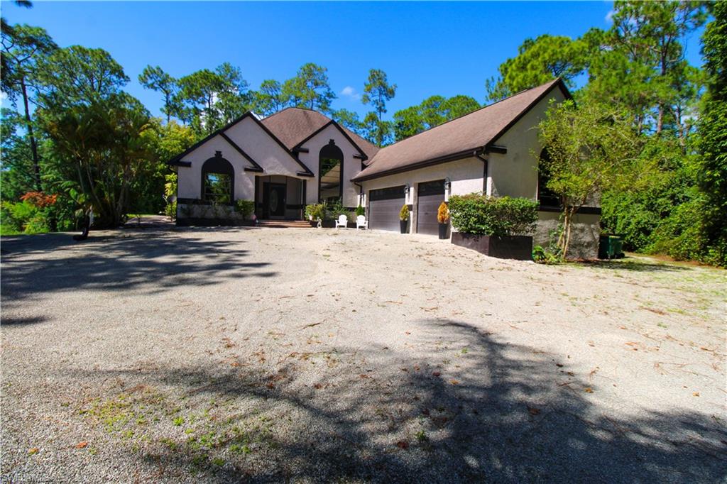 311 31st Street Northwest Naples, FL 34120 - Photo 7 of 50 a front view of a house with a dirt yard and a large tree
