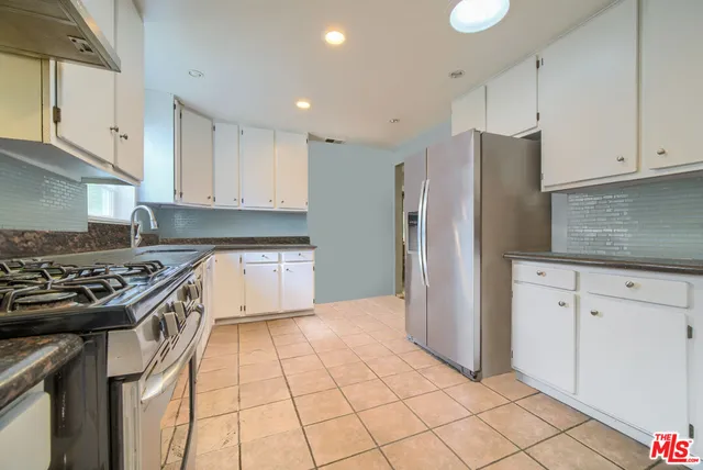 a kitchen with stainless steel appliances granite countertop a stove a refrigerator and a white cabinets