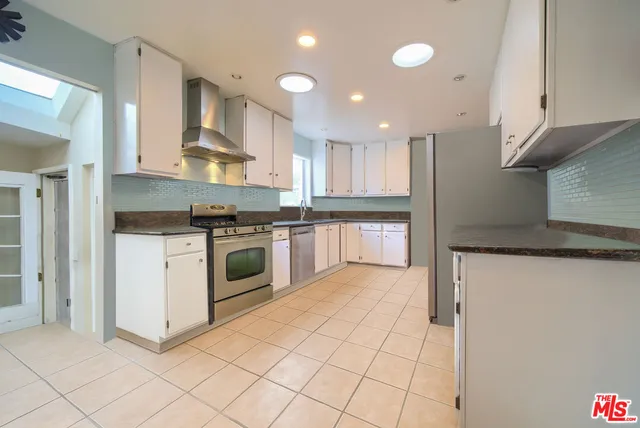 a kitchen with stainless steel appliances granite countertop a stove a sink and a refrigerator