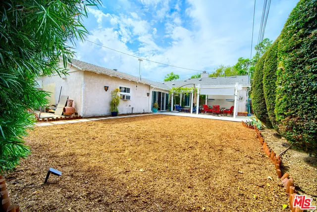 a view of yellow house with large trees