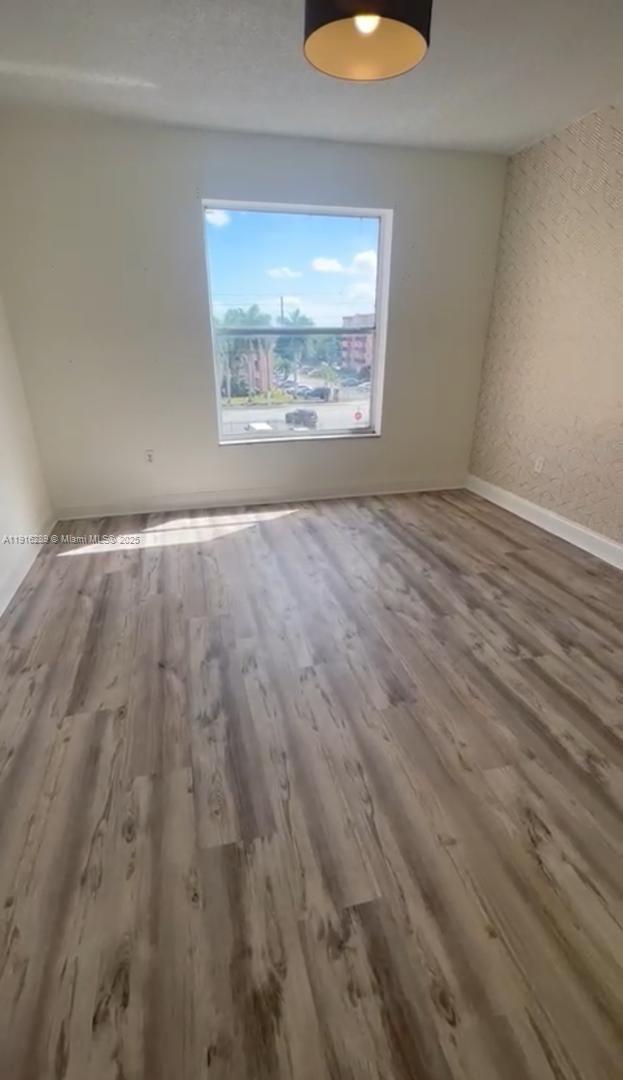 5201 Northwest 7th Street, Unit 405 Miami, FL 33126 - Photo 6 of 10 an empty room with wooden floor and windows