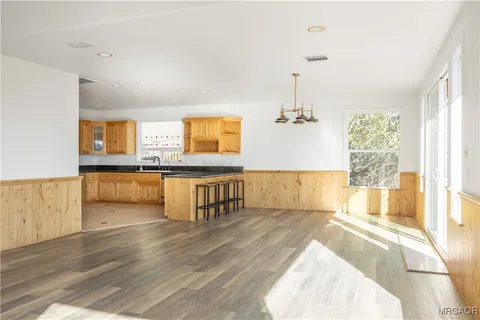 a living room with kitchen island granite countertop wooden floor and a sink