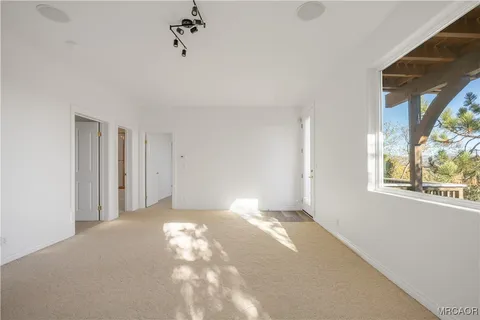 a view of a big room with windows and chandelier fan