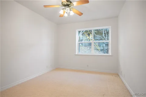 an empty room with a window and a fan