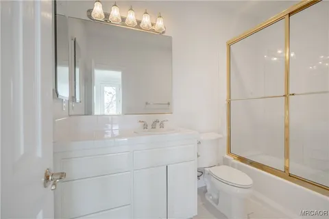 a bathroom with a sink a toilet a mirror and shower