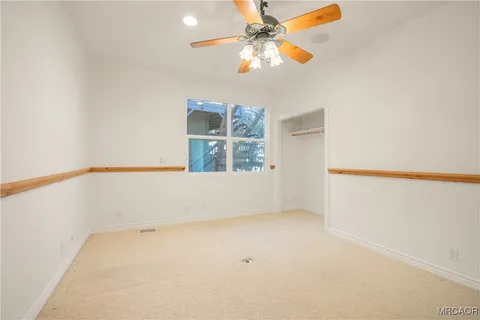 an empty room with a window and a ceiling fan