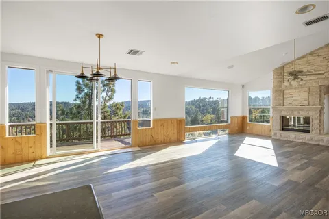 a view of an empty room with wooden floor and a fireplace