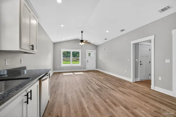 a view of an empty room with wooden floor and a sink