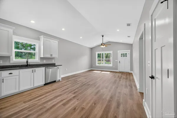 a large kitchen with granite countertop a large window and wooden floor