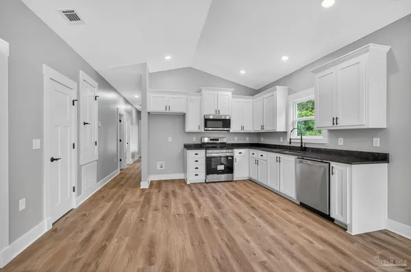 a kitchen with granite countertop a stove top oven a sink and cabinets