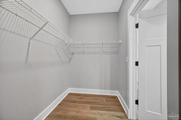 a view of a hallway with wooden floor and a bathroom