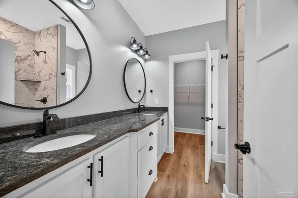 a bathroom with a granite countertop double vanity sink and a mirror