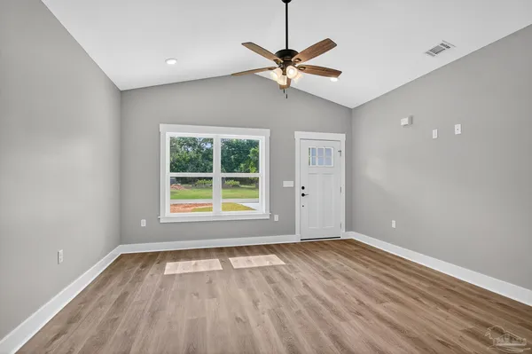 a view of an empty room with wooden floor and a window