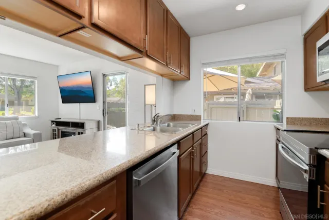 a kitchen with stainless steel appliances granite countertop a sink a stove and a wooden cabinets