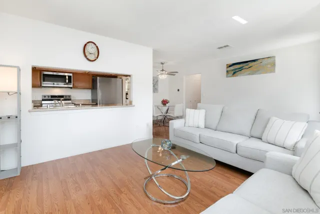 a living room with furniture a flat screen tv and kitchen view