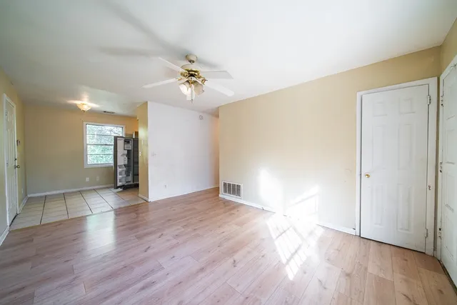 a view of an empty room with window and wooden floor