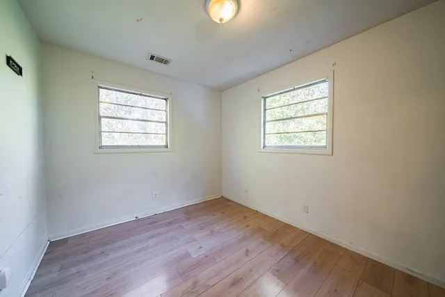an empty room with wooden floor and windows