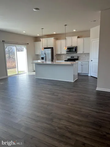 a large kitchen with stainless steel appliances granite countertop a stove a sink and white cabinets