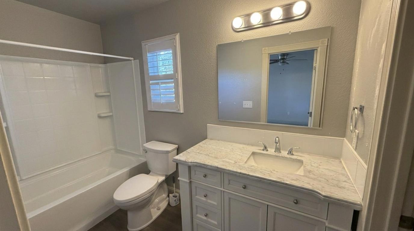 1416 San Rafael Street Los Banos, CA 93635 - Photo 13 of 21 a bathroom with a granite countertop sink toilet a shower and a mirror