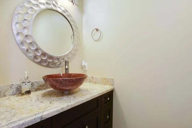a bathroom with a granite countertop sink a mirror and vanity