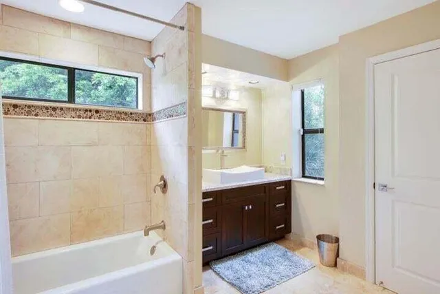 a bathroom with a granite countertop sink a mirror and a bathtub