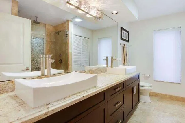 a spacious bathroom with a granite countertop sink a large mirror and a bathtub