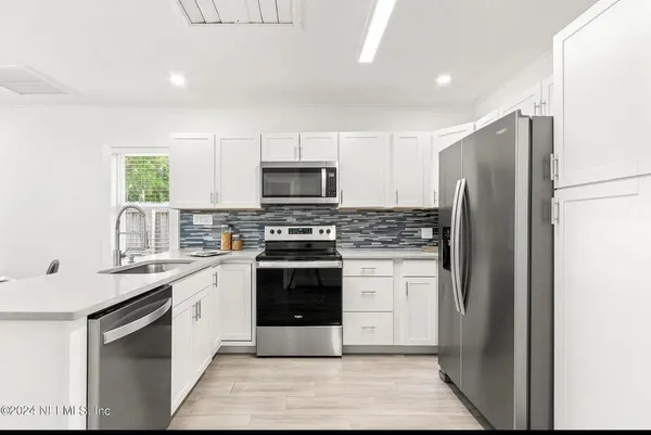 a kitchen with white cabinets stainless steel appliances and a sink