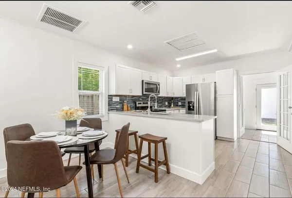 a kitchen with stainless steel appliances kitchen island granite countertop a table chairs and a refrigerator