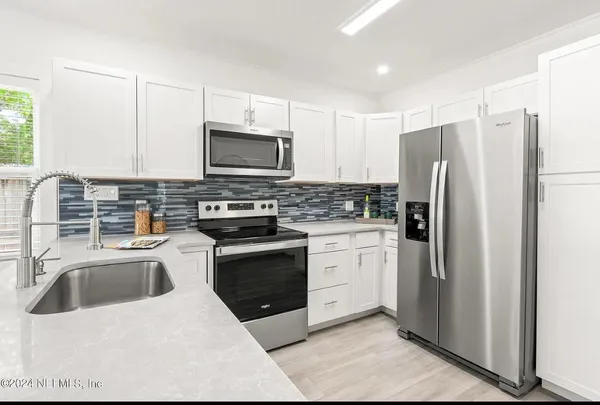 a kitchen with granite countertop a refrigerator sink and stove