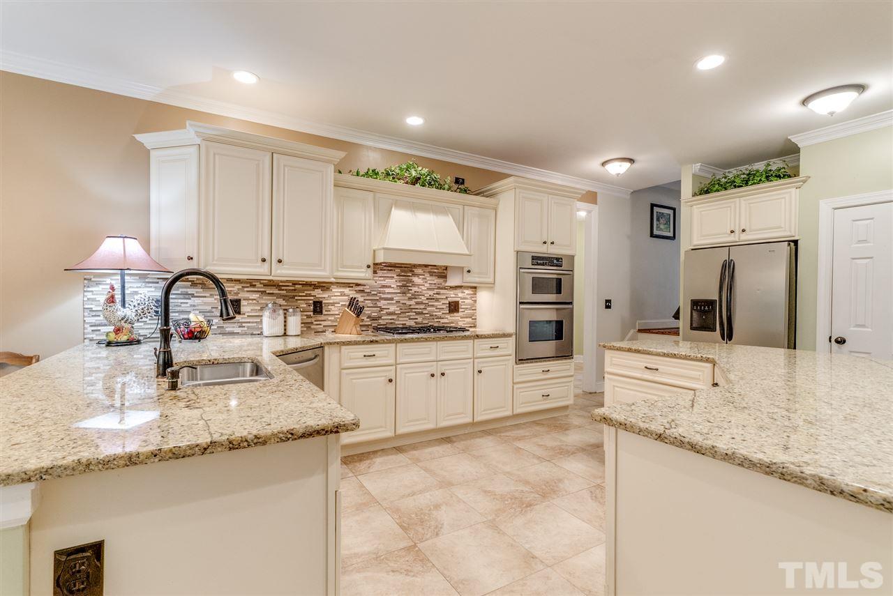 1701 Crown Glenn Place Raleigh, NC 27613 - Photo 14 of 25 a kitchen with granite countertop a sink stove refrigerator and cabinets