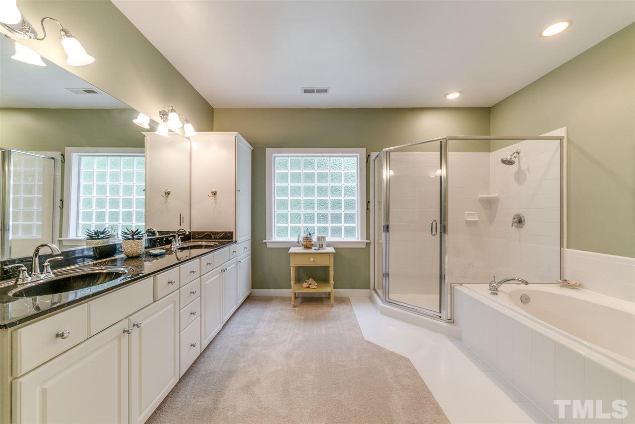 1701 Crown Glenn Place Raleigh, NC 27613 - Photo 19 of 25 a large bathroom with a double vanity sink a large mirror and a bathtub