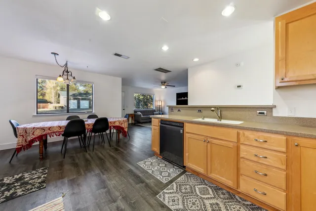 a open kitchen with stainless steel appliances granite countertop a stove a sink a dining table and chairs with wooden floor