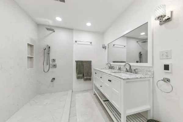 a bathroom with a double vanity sink toilet mirror and shower