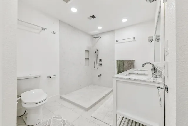 a spacious bathroom with a granite countertop sink a toilet and a mirror