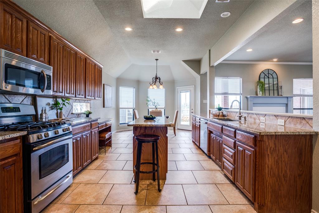 a large kitchen with stainless steel appliances granite countertop a stove a sink and a microwave