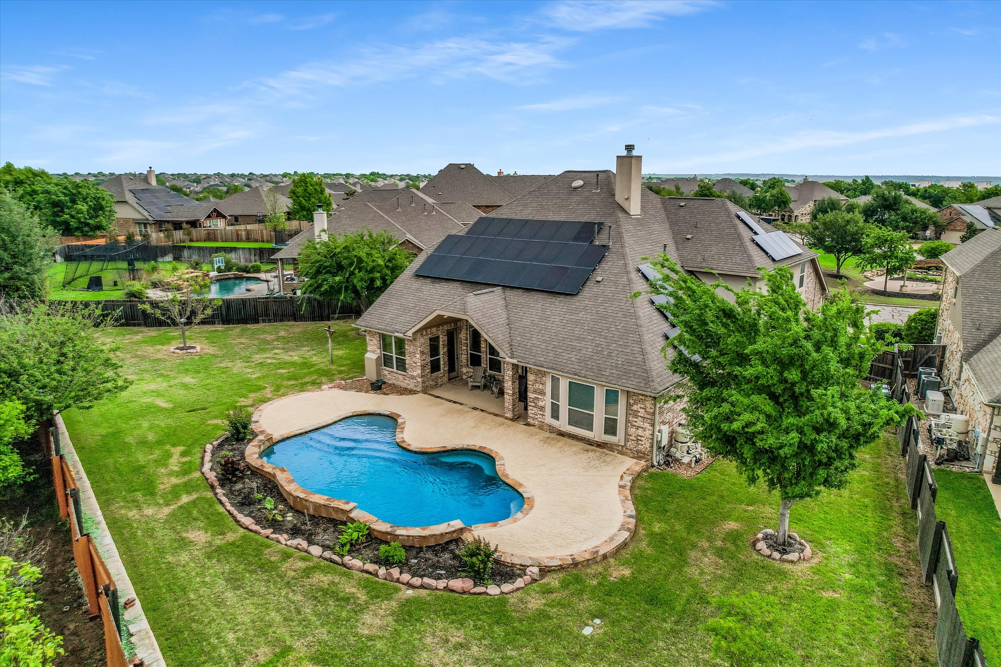 4381 Nash Ranch Loop Round Rock, TX 78665 - Photo 1 of 1 The property features a brick exterior, a private swimming pool with a stone surround, and an expansive lawn with mature trees